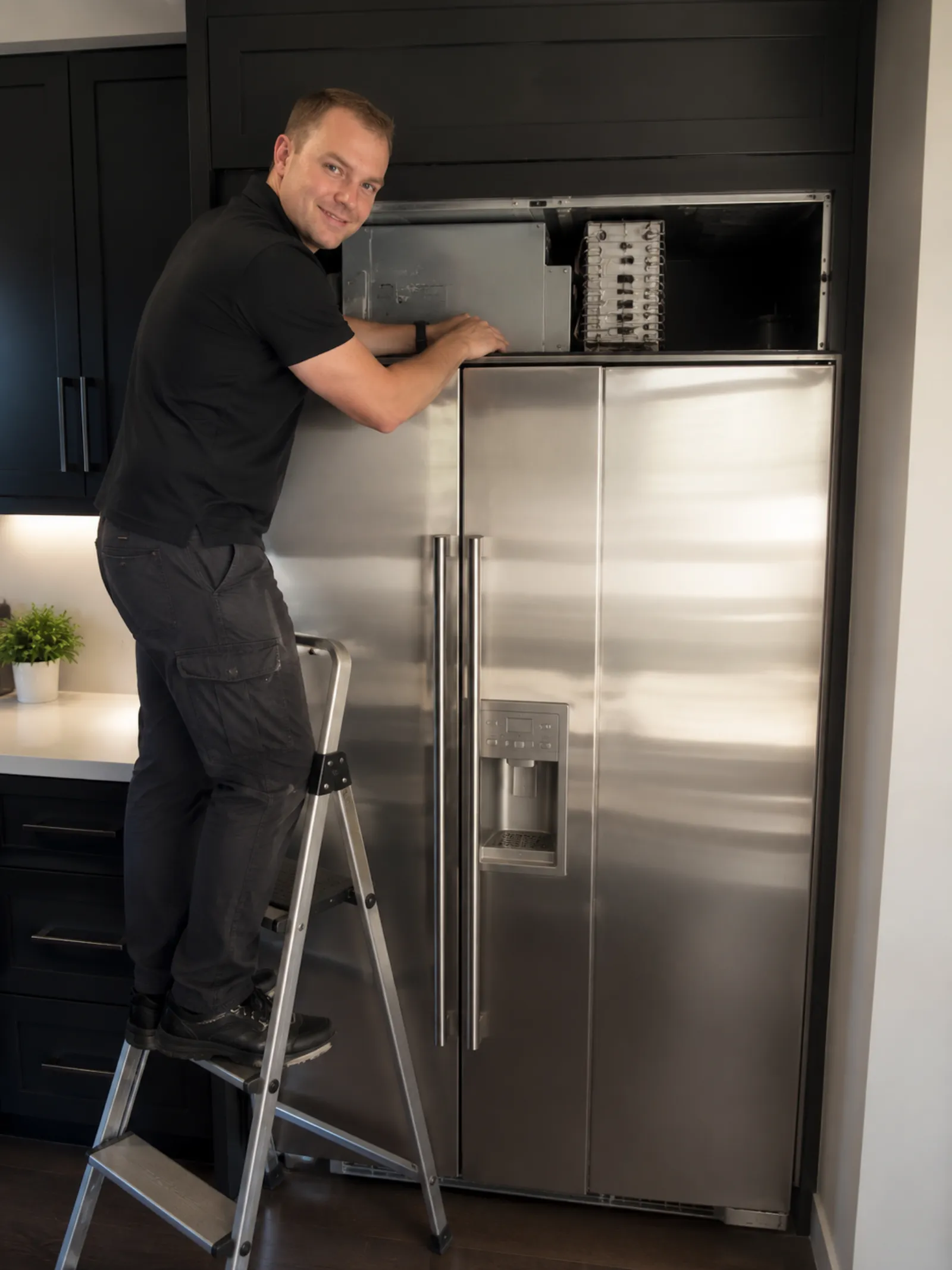 Technician repairing a built-in Sub-Zero refrigerator in a Los Angeles kitchen