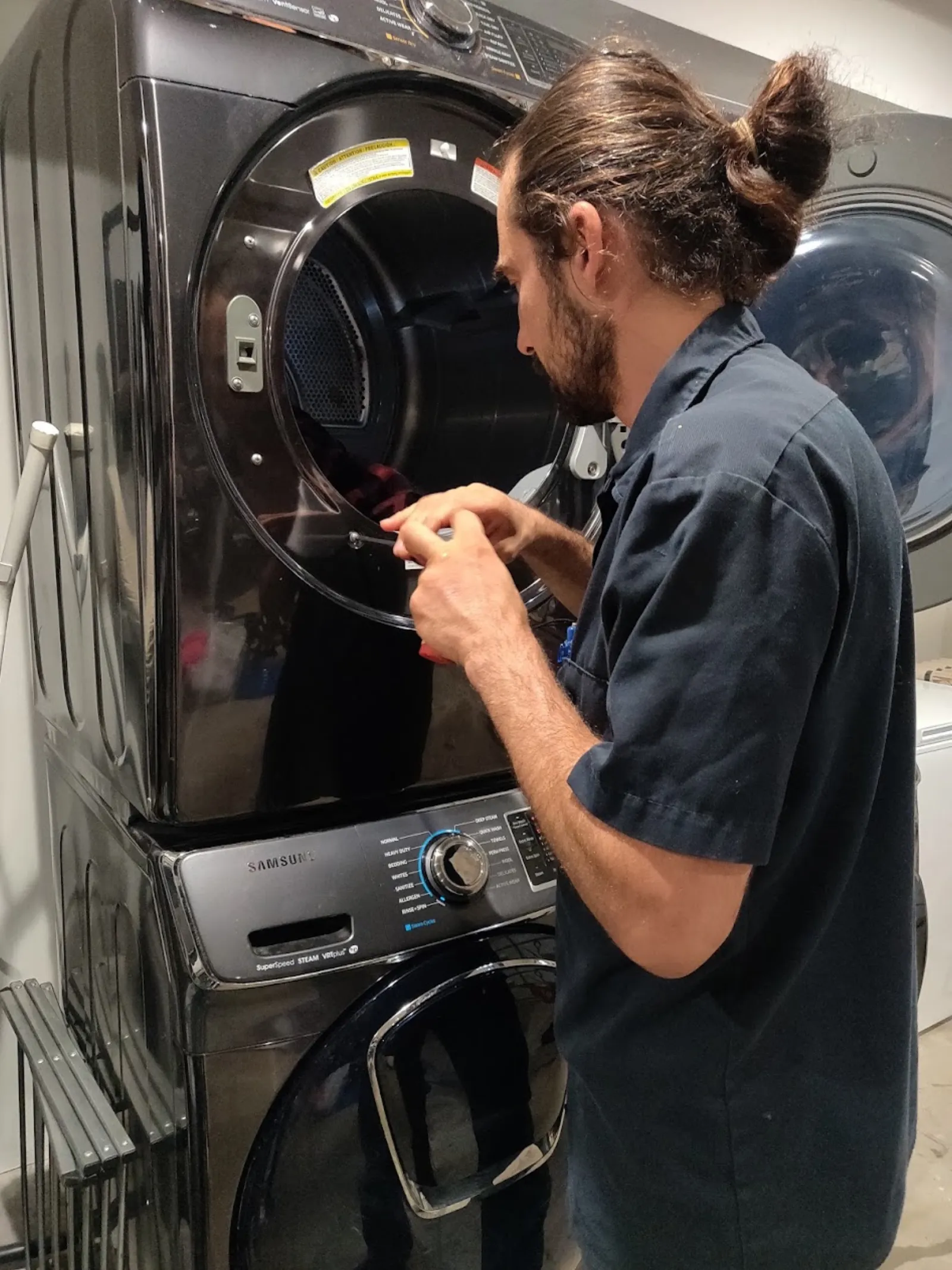 Technician inspecting a stackable washer dryer unit for dryer vent fire risk signs